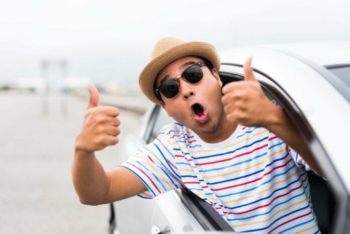 Happy man showing thumbs up in car