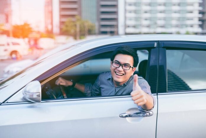 Young man driving car thumbs up