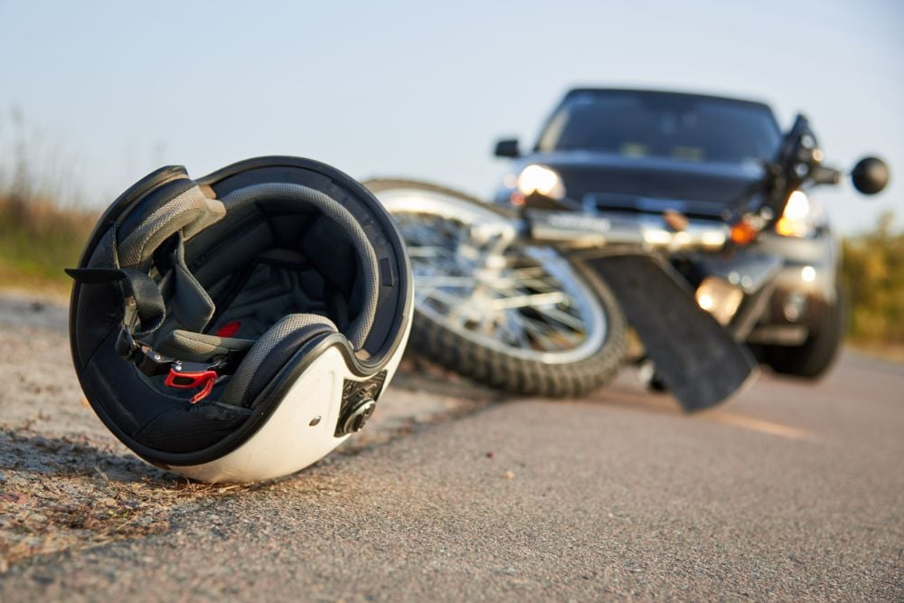 Motorcycle and helmet on the road with car in the background