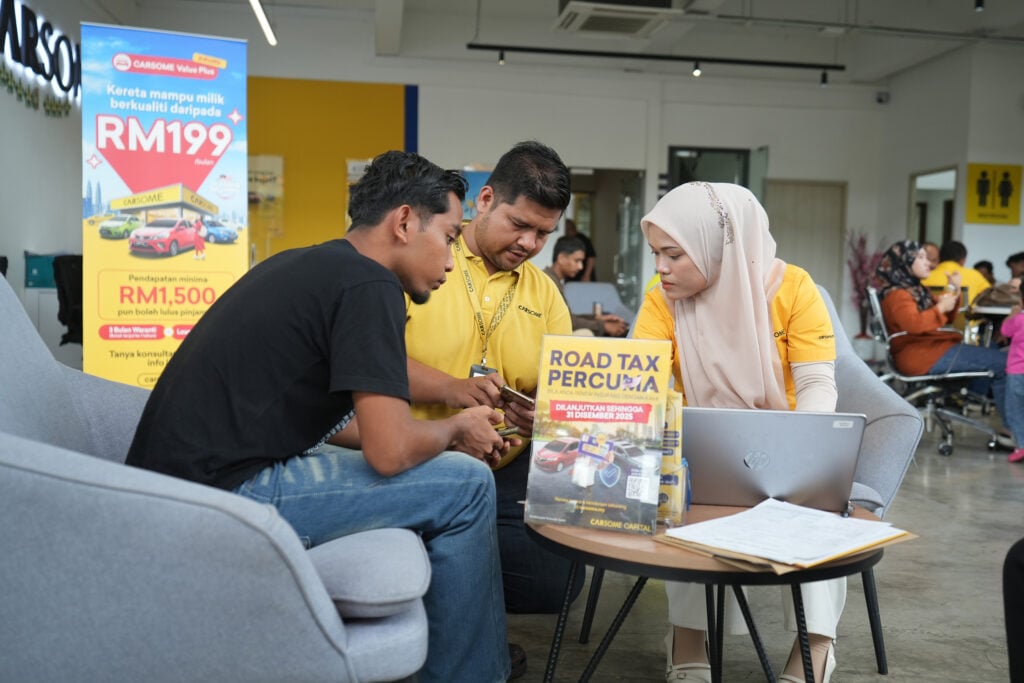 CARSOME sales advisor explaining car features to two buyers inside showroom