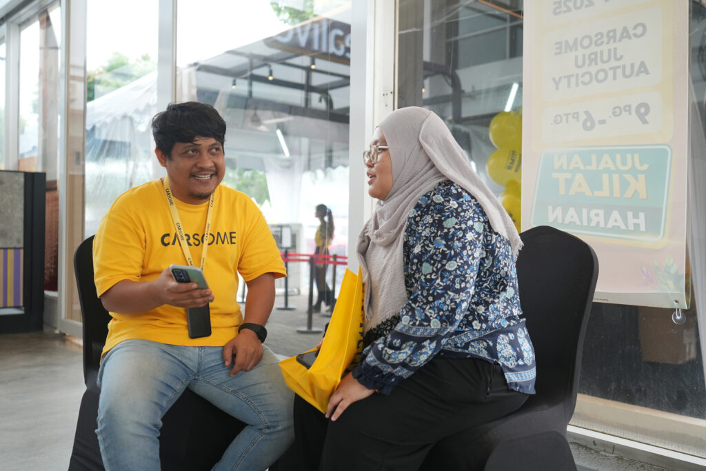 Penasihat jualan CARSOME menerangkan ciri kereta kepada pembeli di dalam bilik pameran