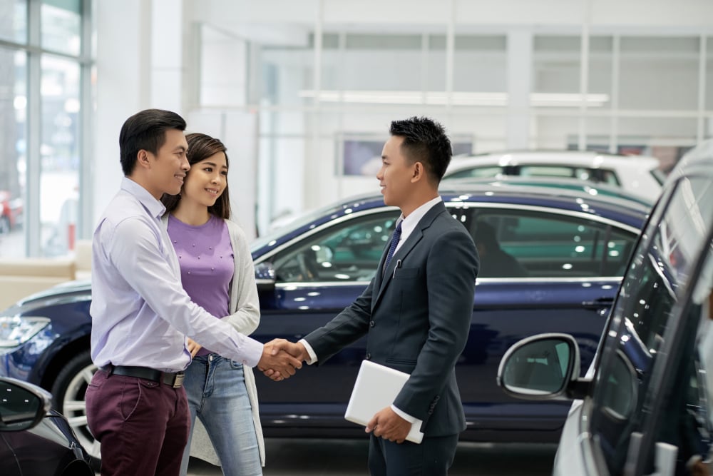 couple and car salesperson in car dealership